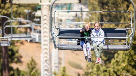 Two girls on a sky chair ride.