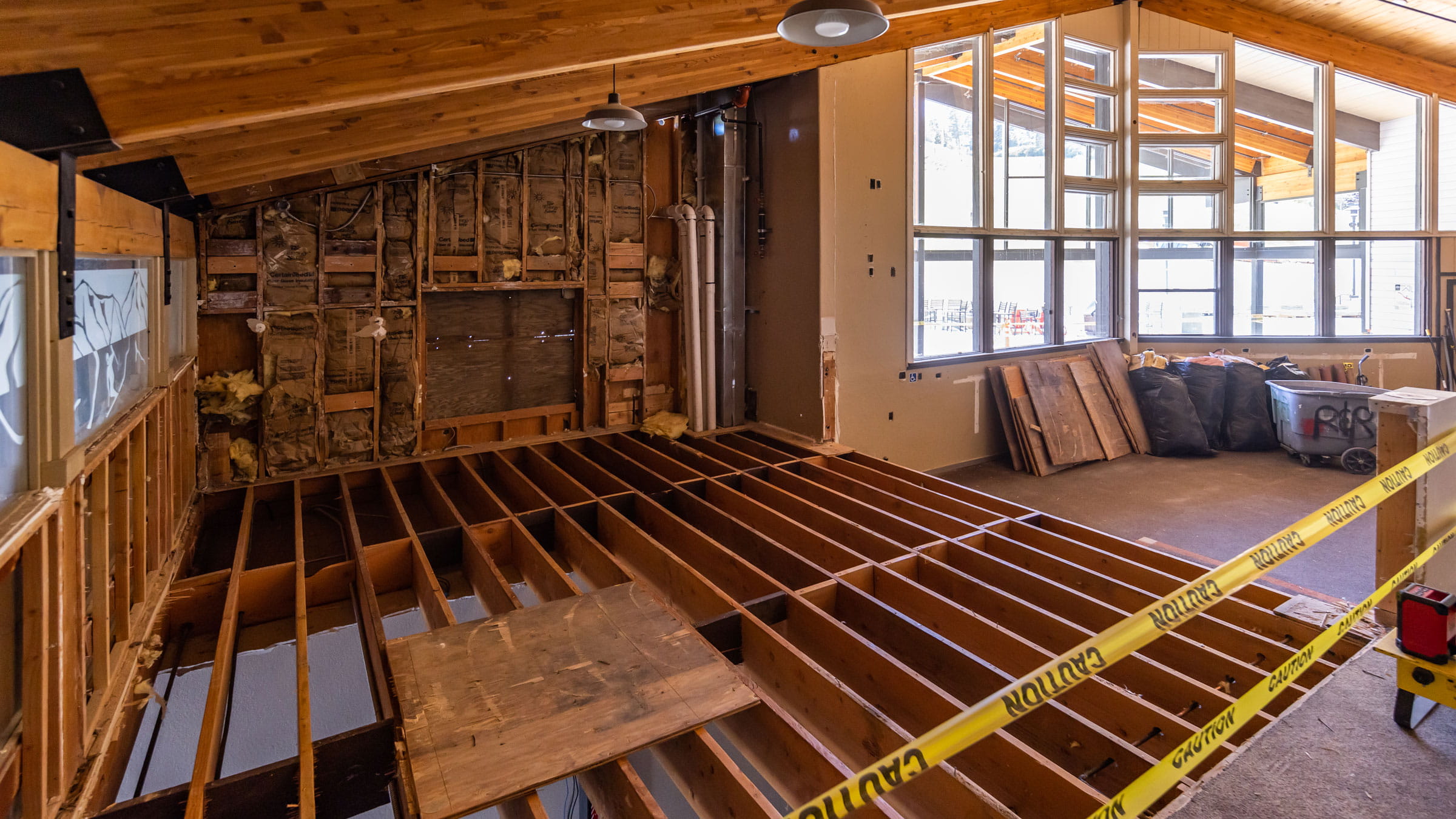Construction workers with orange cones demolitioning an indoor deck
