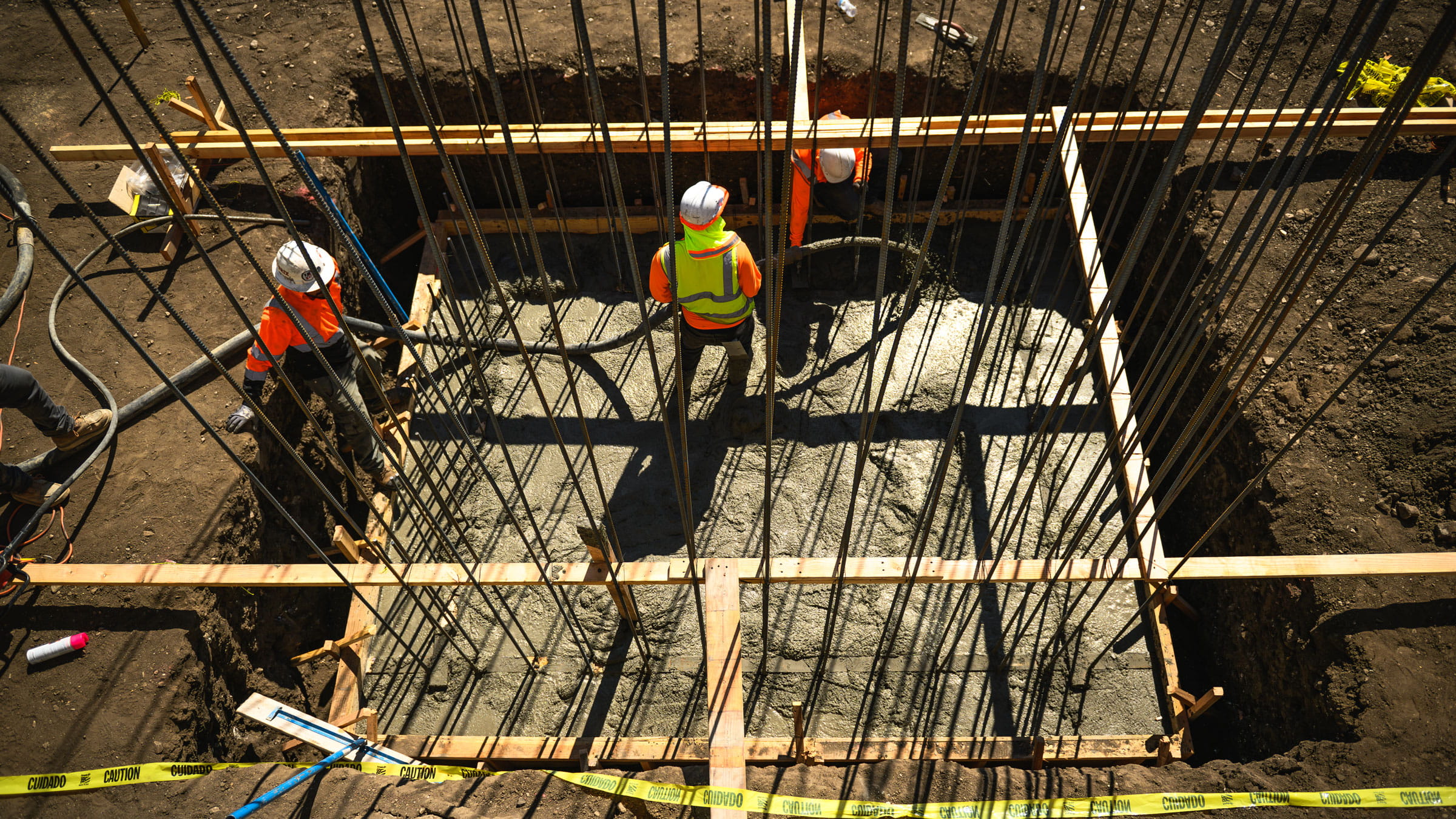 Construction workers on dirt with metal and wood features surrounding.