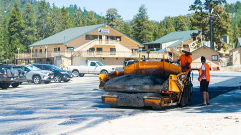 Construction workers in Snow Valley parking lot on asphalt paver.