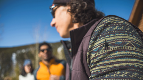 Close up photo of a Smartwool fleece on a man with two people in the distance