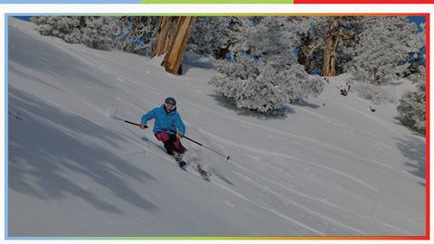 Tinted photo of skier in blue jacket doing down a ski slope at Snow Summit in the winter months