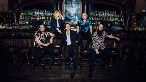 The Mowgli's band posing for the camera in a dark and dimly lit bar