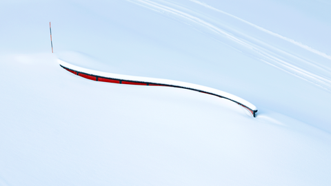 An s-rail terrain park feature, located at Bear Mountain, with fresh snow on top of the rail and surrounding it.