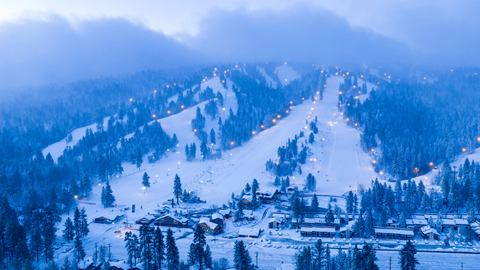 An arial drone image of Snow Summit slopes, including the base area buildings and parking lot, covered in snow after a fresh snow storm.