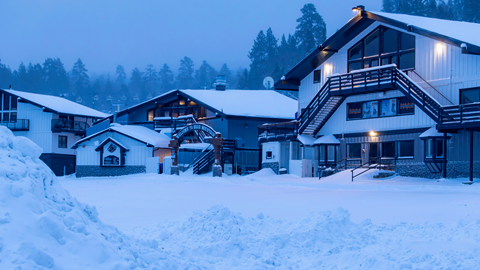 Parking lot view, looking at the base area buildings at Bear Mountain, with fresh snow on the ground and rooftops. 
