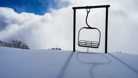 The photo opt stand alone chairlift at the top of Snow Valley's Chair 1 with fresh untouched snow on the ground and white clouds in the background with blue skies peeking out.