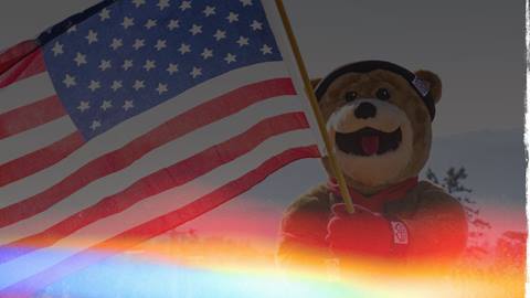 The Big Bear Mountain Resort mascot, Biggie Bear, holding an American flag in honor of Independence Day.