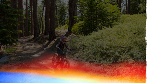 Young female mountain biker with a full face helmet biking through the forest