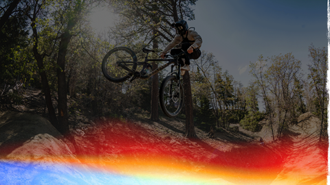 Mountain biker doing a trick where they are in the air in front of their bike