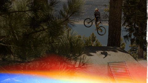 Snow Summit bike park opening day, mountain biker high jumping off a wooden ramp