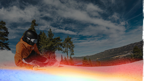 Snowboarder going downhill on a slope with Big Bear Lake in the background