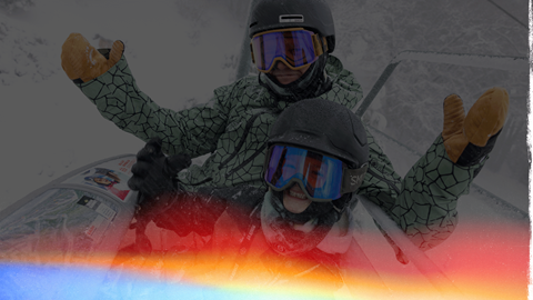 Dad and son on a chairlift about to go snowboarding looking at the camera smiling