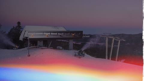 Early morning sunrise over the top chairlift at Bear Mountaing with snow on the trails and a snow gun blowing machine made snow.