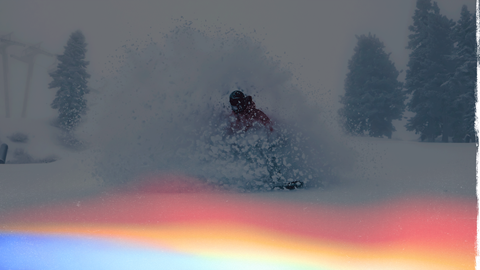 Snowboarder riding through fresh powder on a storm day in Big Bear Lake