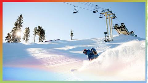 Snowboarder under the chairlift slashing in fresh snow