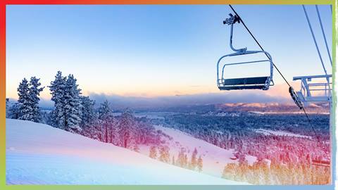Sunrise photo of a chairlift looking down into trees covered with snow