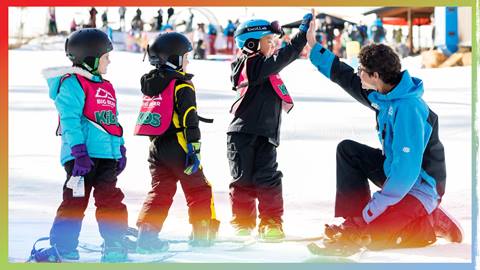 Snowboard instructor high fiving a kiddo in a group lesson
