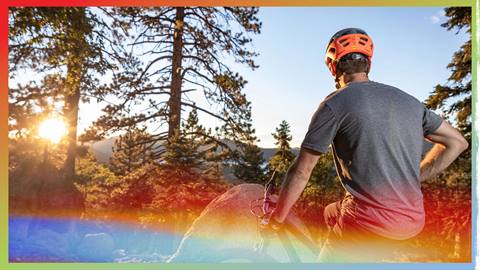 A mountain biker taking a break and checking out the forest views as the sun sets