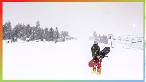 snowboarder standing on the snow with her board while snow is falling