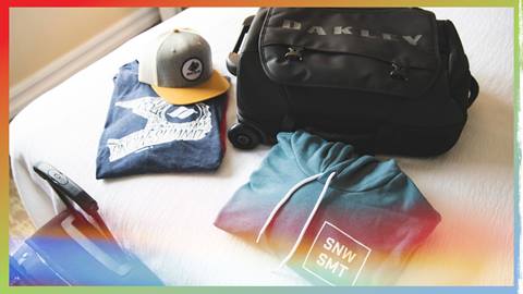 Luggage bag, hat, shirt, and sweatshirt laying on bed in hotel room