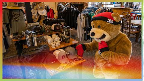 Biggie the mascot kneeling down at a retail clothing table at the Bear Mountain Golf Course Pro Shop