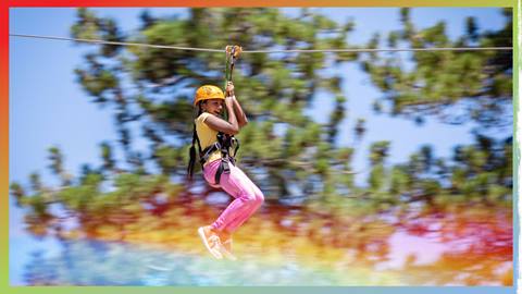 young adult zip lining through the forest at snow summit