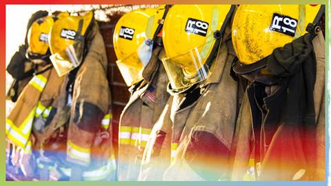 Five fire fighter uniforms and helmets hung up on a wall