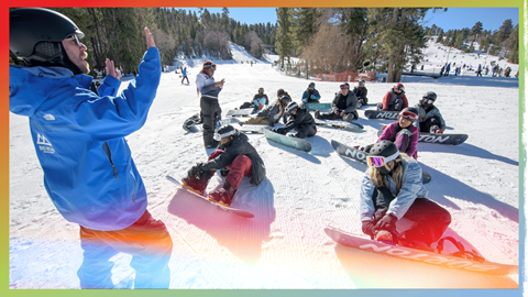 Snowboard instructor in front of a group of snowboarders learning to ride