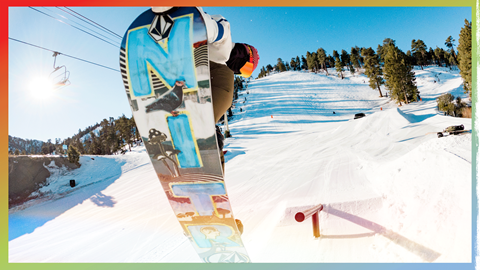 snowboarder in the air grabbing the board after coming off a rail
