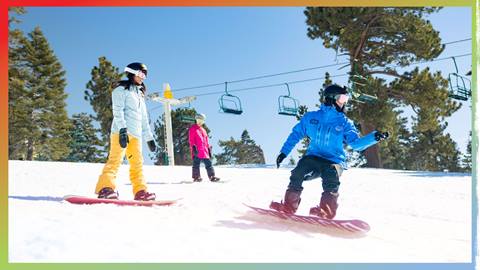 Mother and daughter taking a snowboard lesson with an instructor at Big Bear Mountain Resort