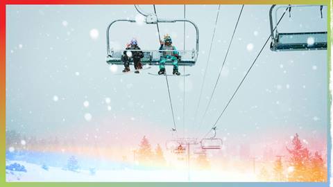 Two adults on snowboards on a chairlift during a winter snow storm.