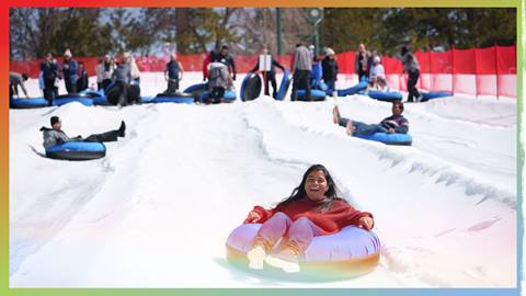 A group of adults on snow tubes flying down the lanes at Snow Valley's Coyote Creek Tube Park