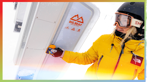 female snowboarder scanning her Ikon Pass to the RFID gates
