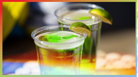 Two green beverages, each in their own clear plastic cups with a lime on the rim.