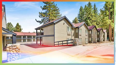 Big Bear Mountain Resort employee two-story housing buildings with dark trim and light color exterior and a paved entrance to the parking lot.