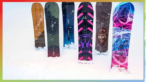 Six snowboards without bindings standing upright in snow