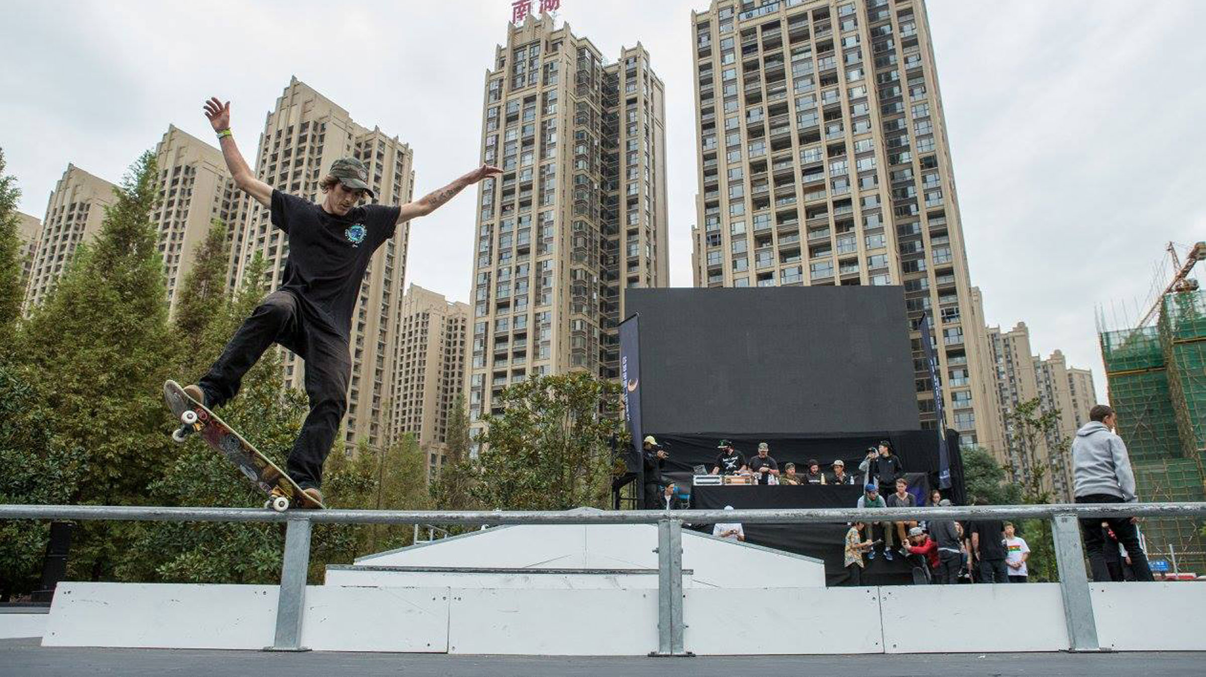 Pro skater, Dave Bachinsky, wearing black shirt and pants doing a rail trick on skateboard during a skate contest.