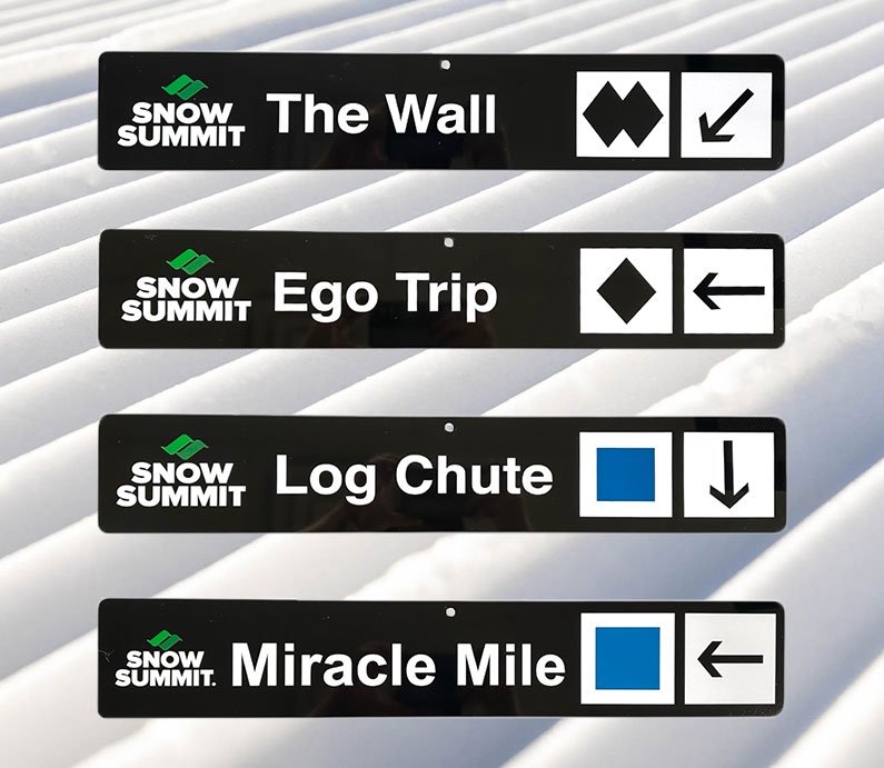 Black trail signs with Snow Summit winter runs: The Wall, Ego Trip, Log Chute, Miracle Mile.