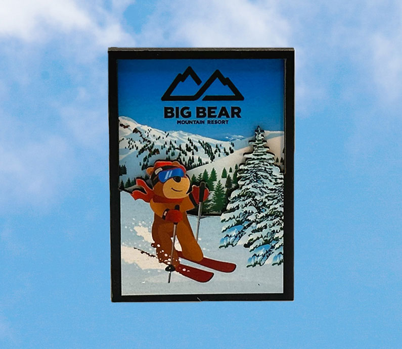 Big bear mountain resort wooden magnet with biggie the bear skiing with mountains snow and trees in background.