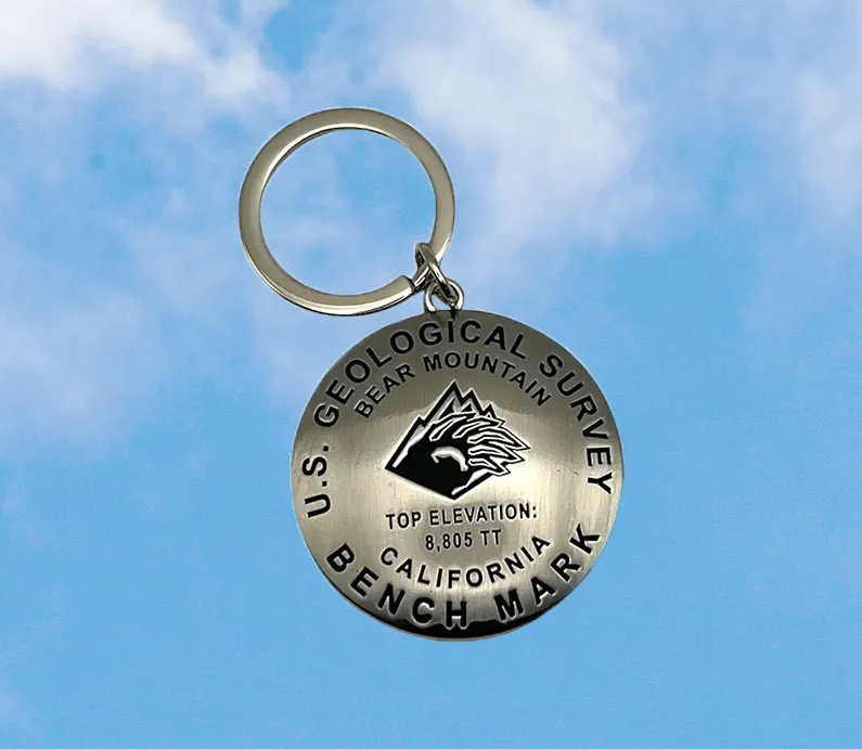 Silver keychain that has a bear mountain logo on it and with Geological Survey Bench Mark/Elevation.