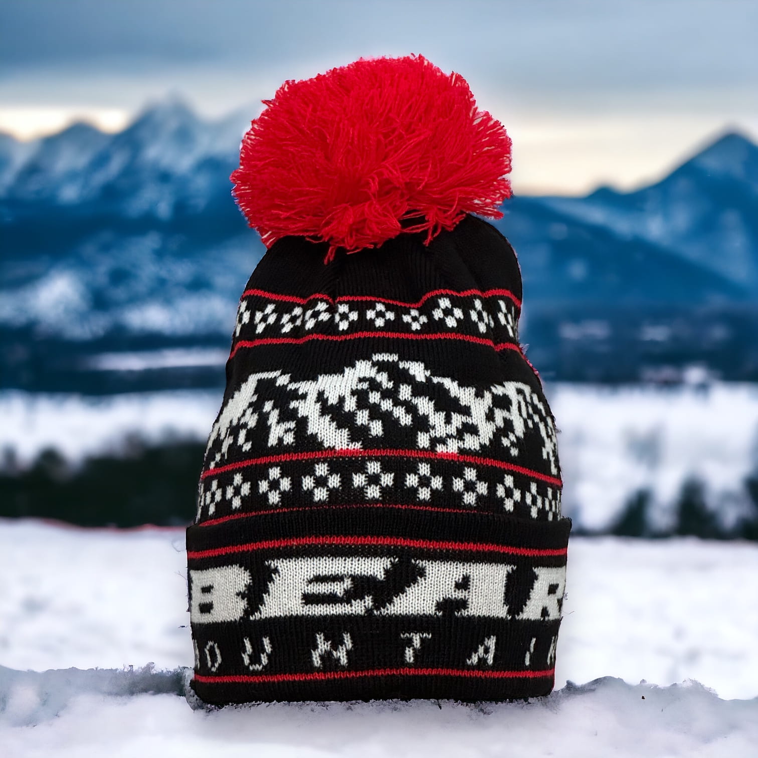 Black Beanie with white bear mountain stitching for the logo and red accent stitching with red pom pom at top.