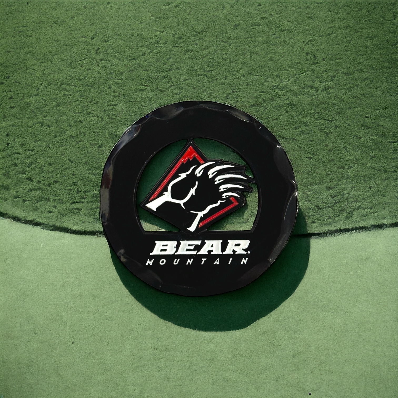Black circular golf ball marker with the Bear Mountain bear claw logo in red and white.