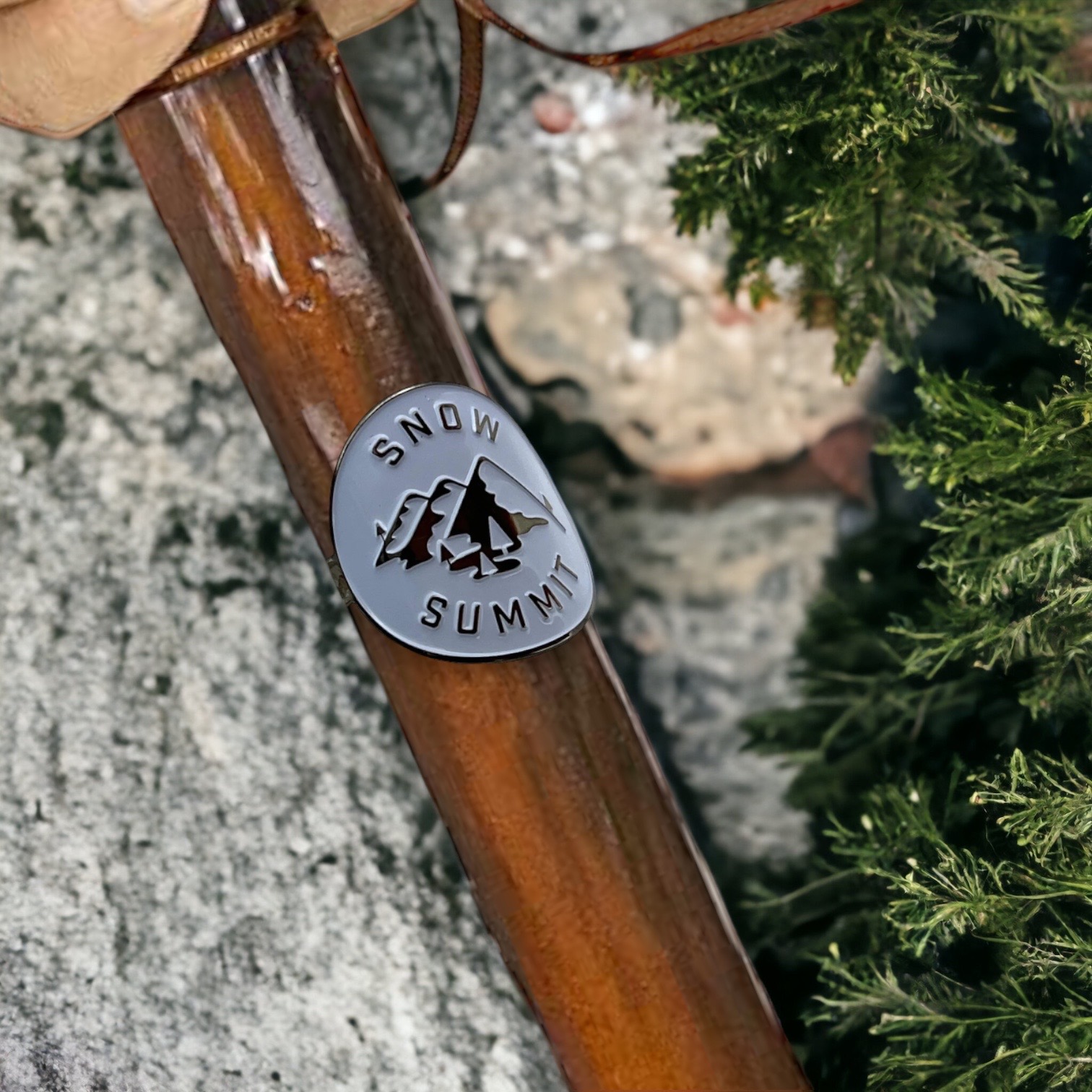 Metal medallion with two screws and a snow summit logo on it