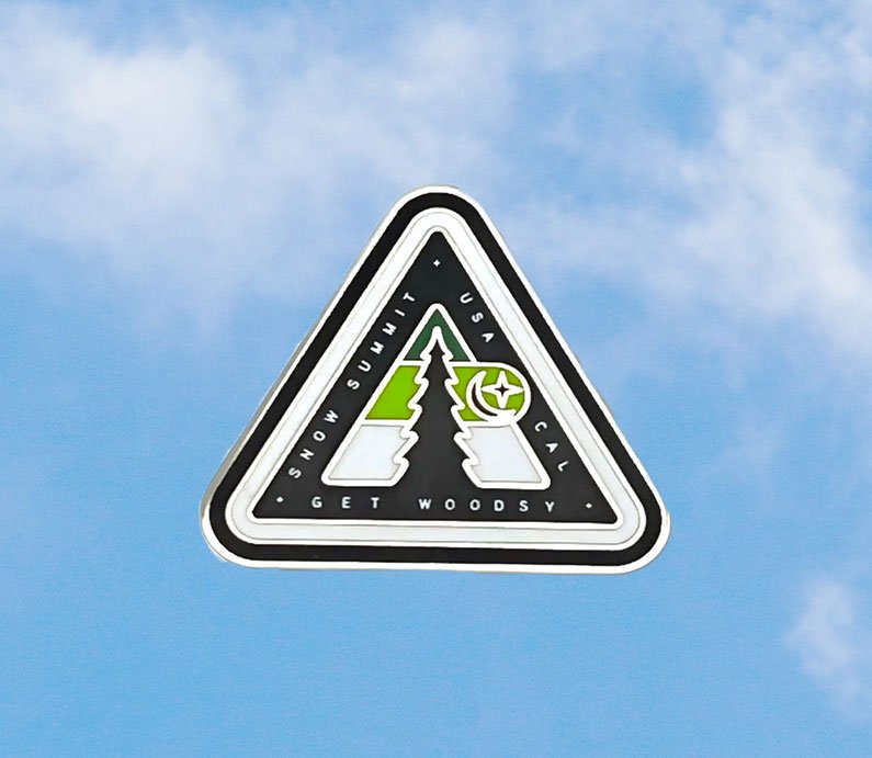 Snow Summit woodsy logo on a magnet with green coloring featuring a pine tree, star, and crescent moon.