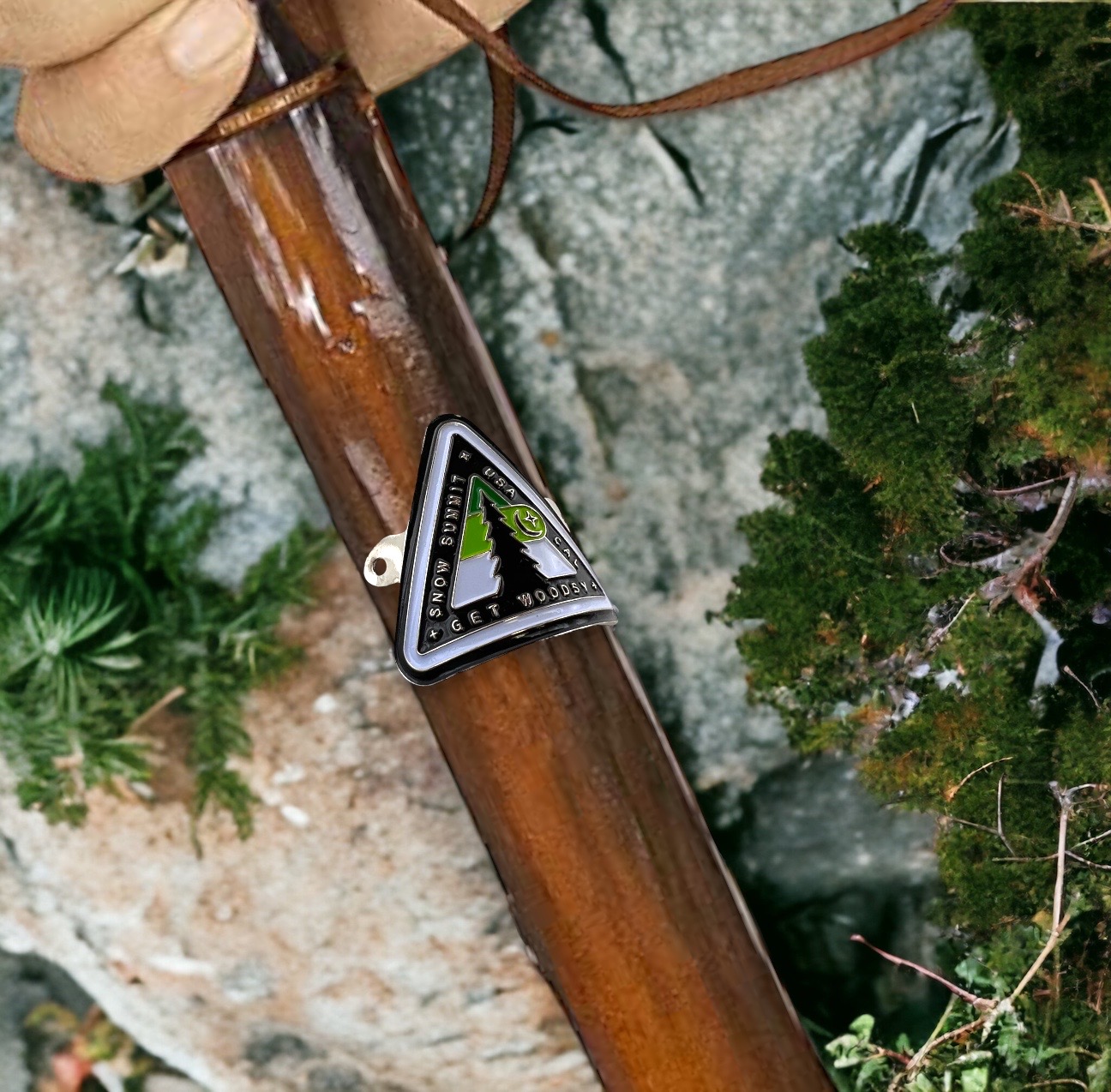 Metal medallion with two screws and a woodsy themed logo on it