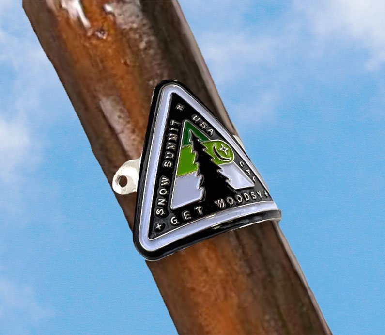 Metal medallion with two screws and a Snow Summit woodsy themed logo on it.