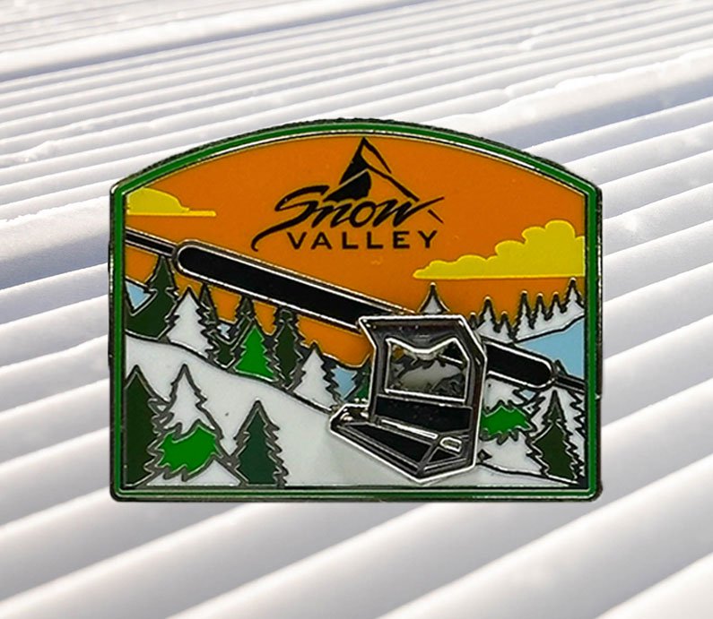 Snow Valley moving chairlift metal pin with a mountain scenery with green pine trees and a orange sky with white clouds.