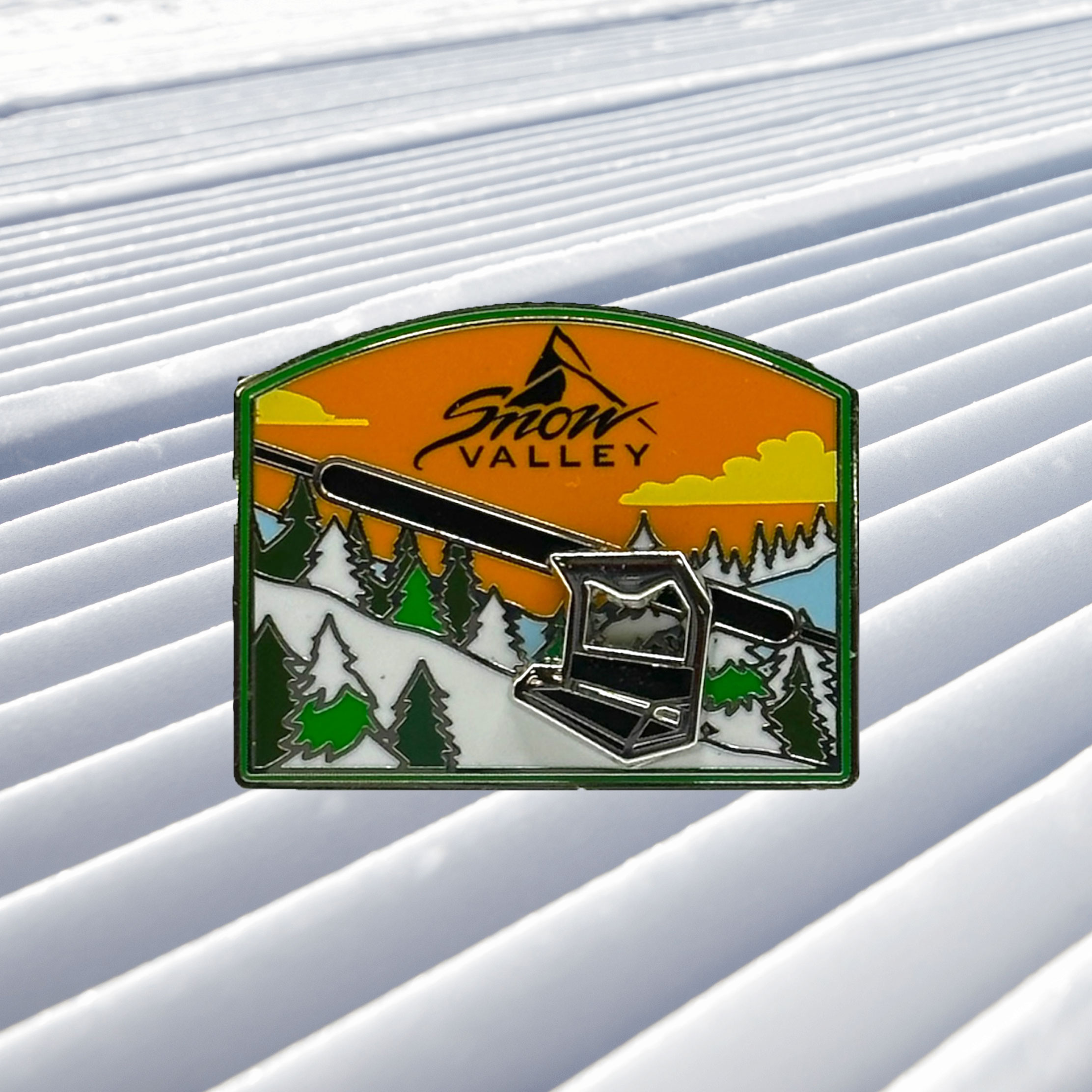 Snow Valley moving chairlift metal pin with a mountain scenery with green pine trees and a orange sky with white clouds