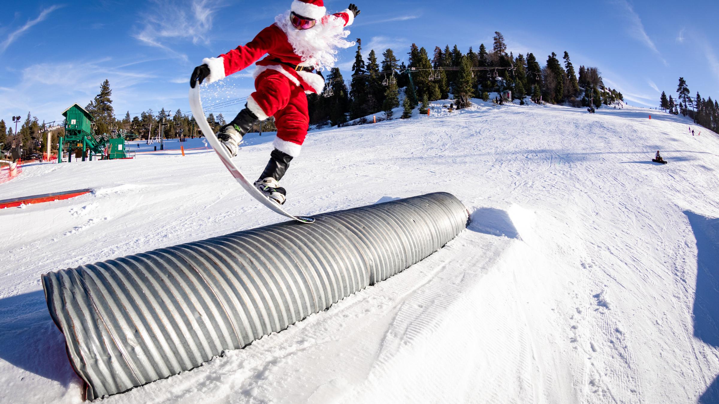 Santa grinding on a snowboard on a rail